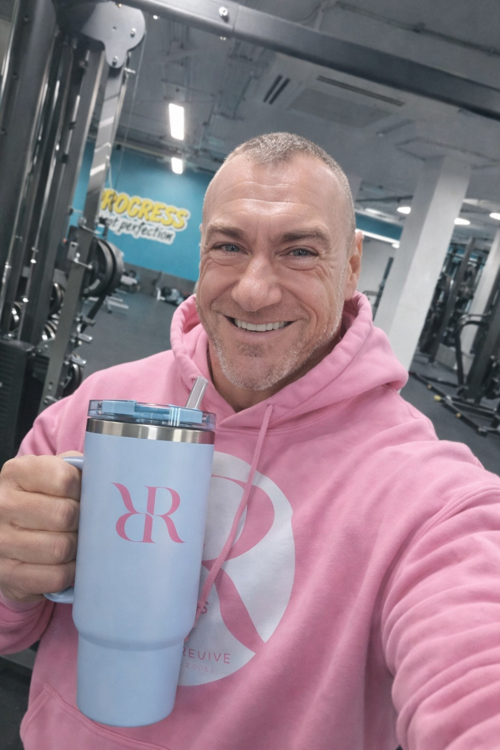 Man smiling in gym holding 40oz hydration tumbler with handle & lid, promoting hydration and fitness.